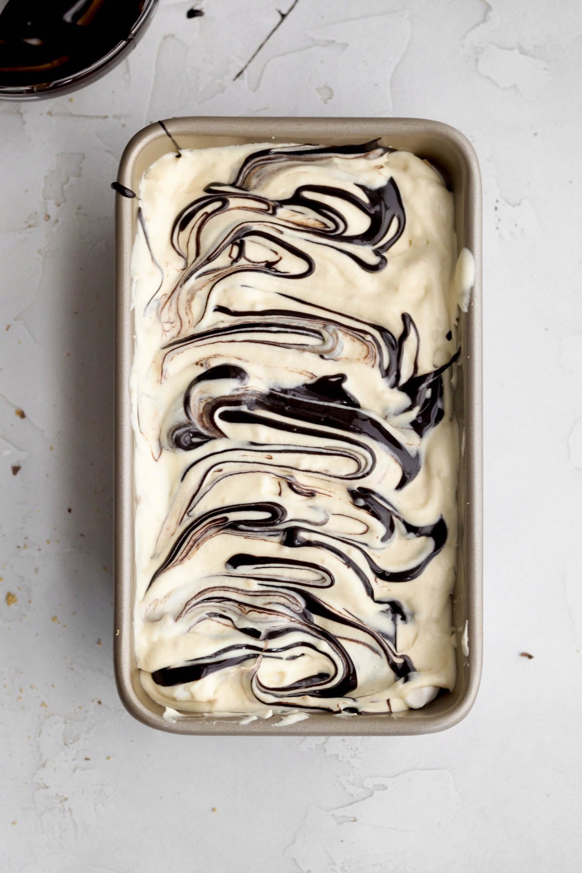 Filling a loaf pan with the base and adding the fudge ripple.