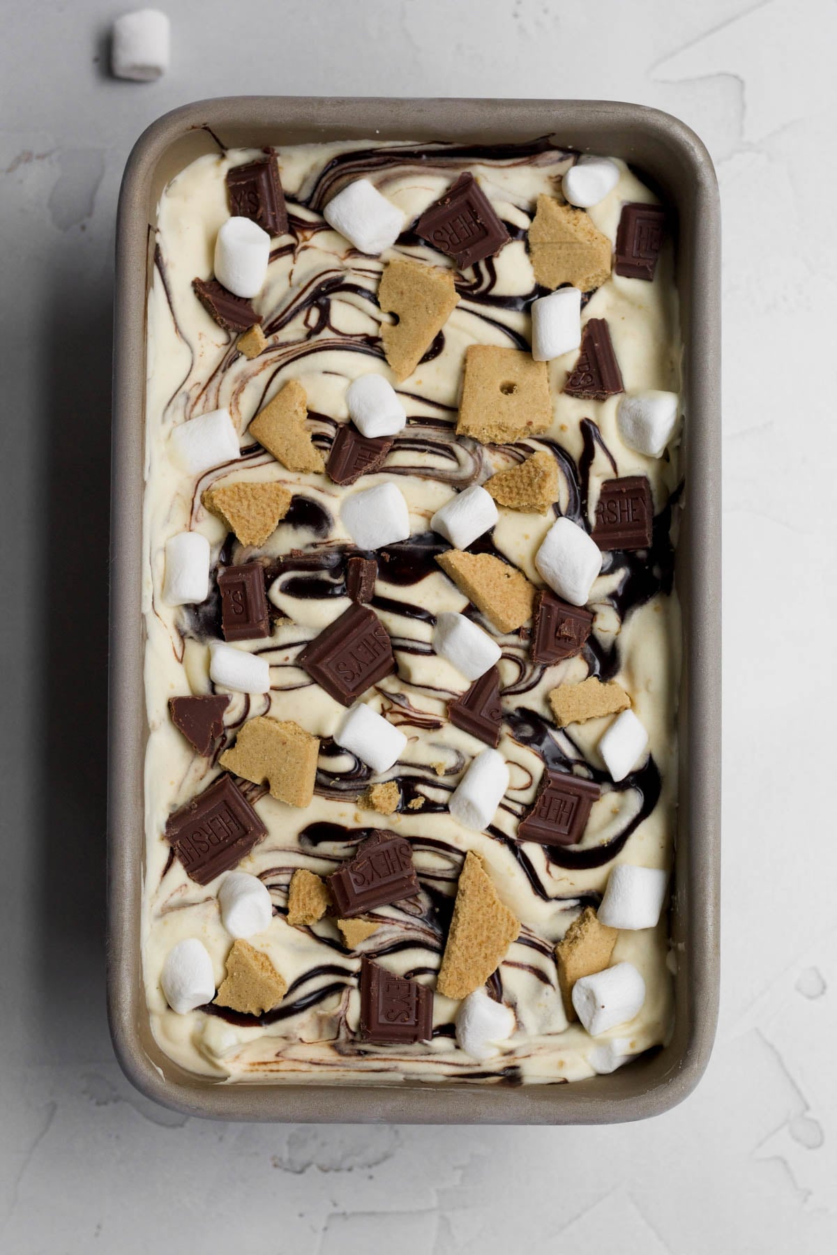Adding small marshmallows and pieces of chocolate bars and graham crackers.