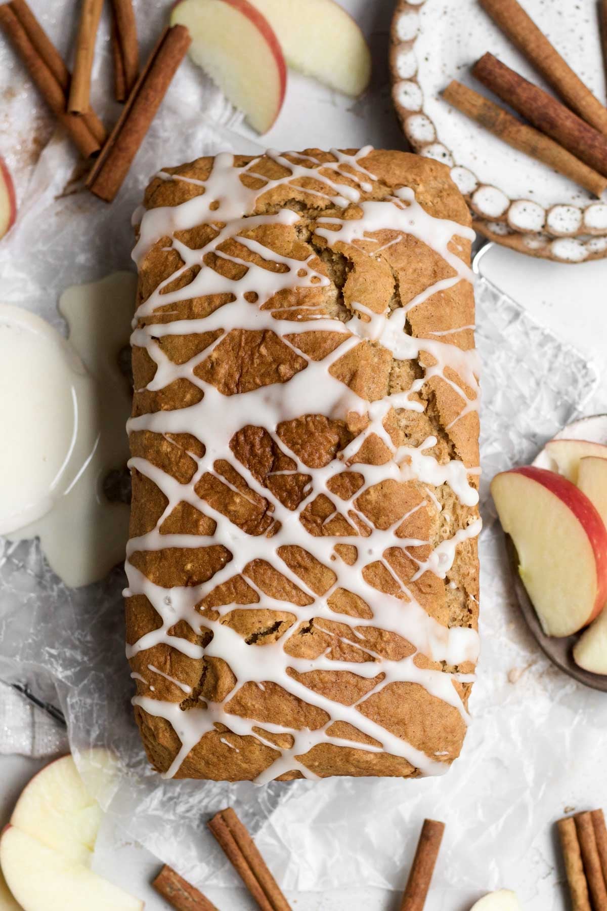 A whole golden-brown apple loaf cake drizzled in a sweet apple glaze.