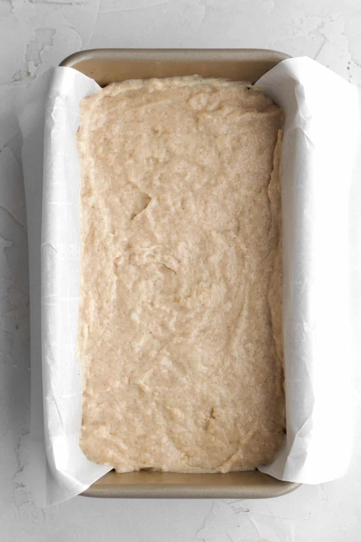 Filling a parchment-lined loaf pan with the batter.