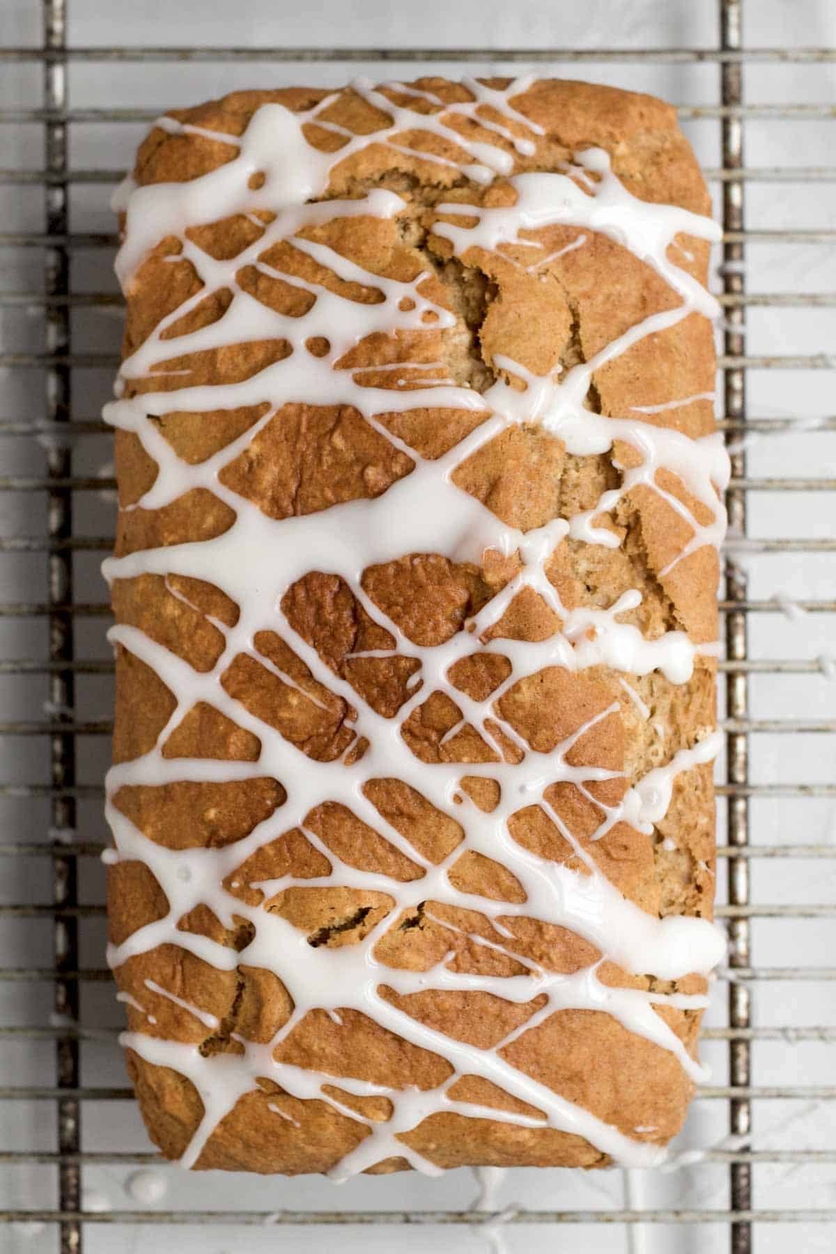 Drizzling the apple glaze of the apple loaf cake in a crosshatch pattern.